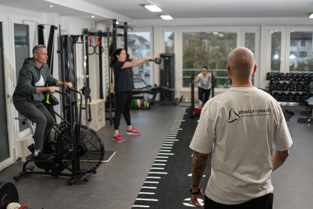 Gruppentraining mit Florian als Trainer – Christoph auf dem Air Bike, Iréne bei Kettlebell Swings und Sabrina beim Schlitten Stoßen bei Absolut You.